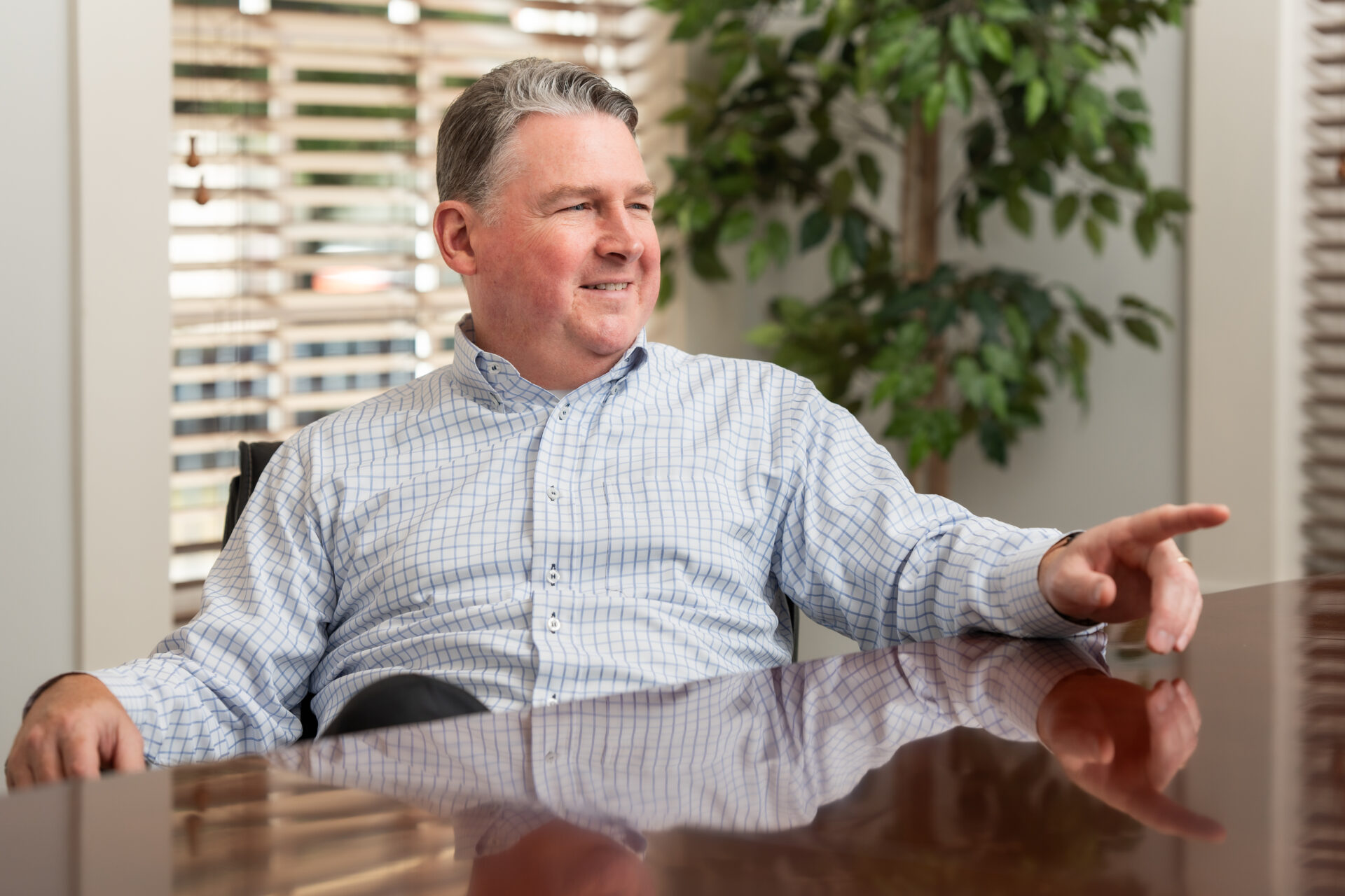 A man sitting at a table with his hand on the remote control.