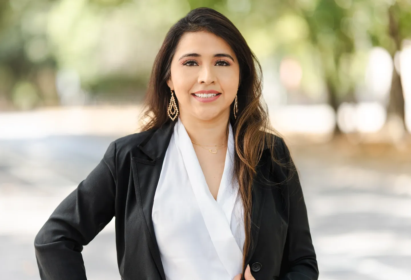 A woman in black jacket and white shirt standing on street.